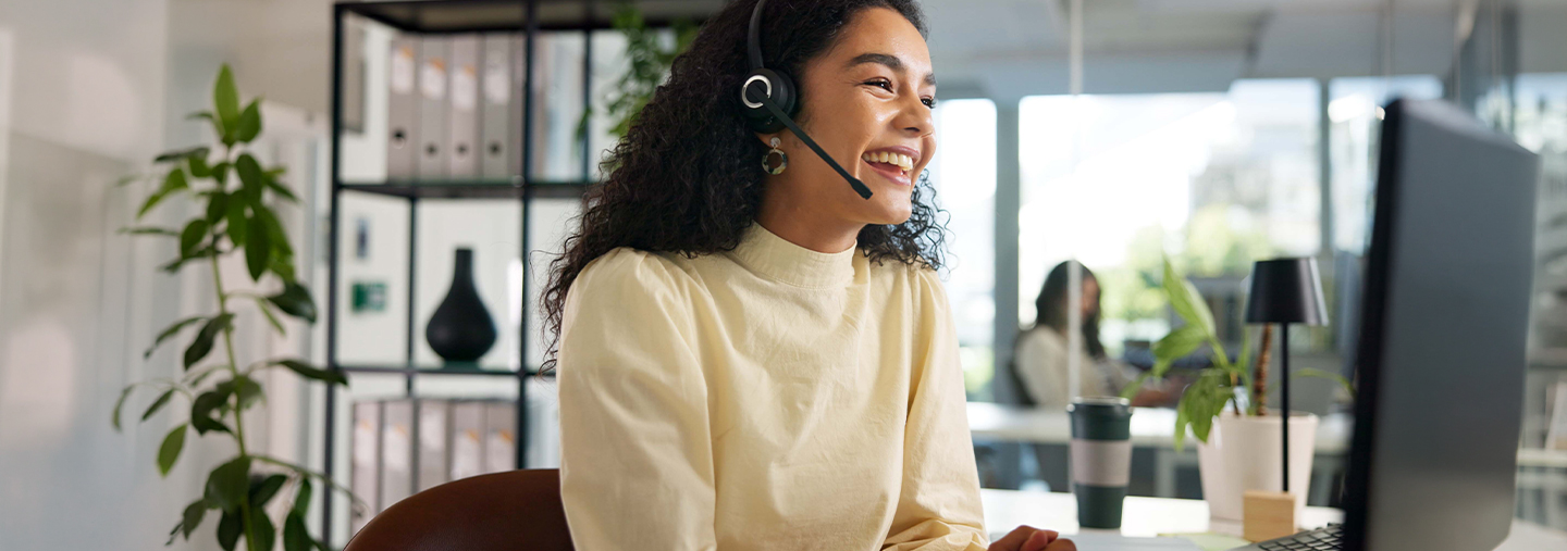 Glückliche Frau mit Headset vor Laptop