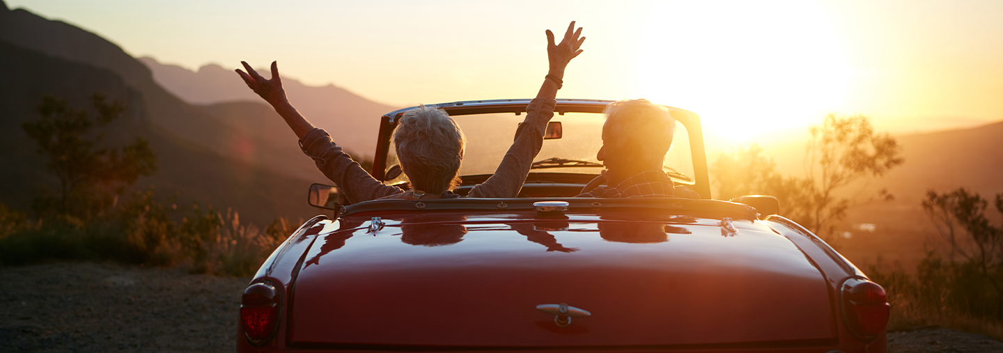 Paar im Cabrio fährt in den Sonnenuntergang