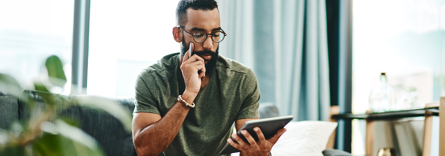 Mann sitzt mit einem Tablet auf einer Couch